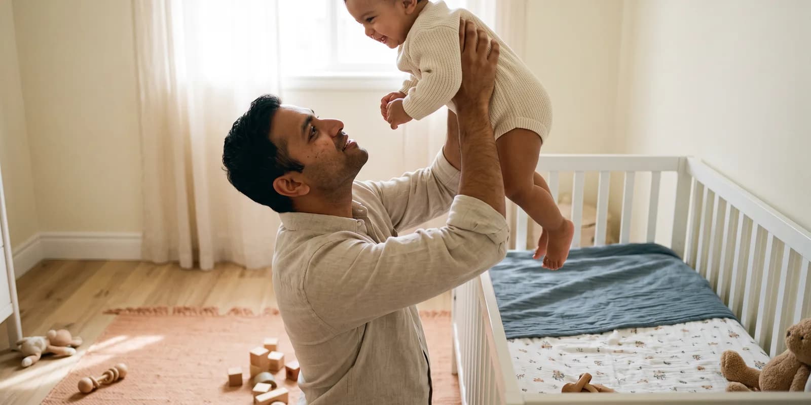 Single adults can adopt at the same minimum age as couples in every state but Georgia A single father lifting his adopted baby in a nursery, showing single adults can adopt at the same ages as couples